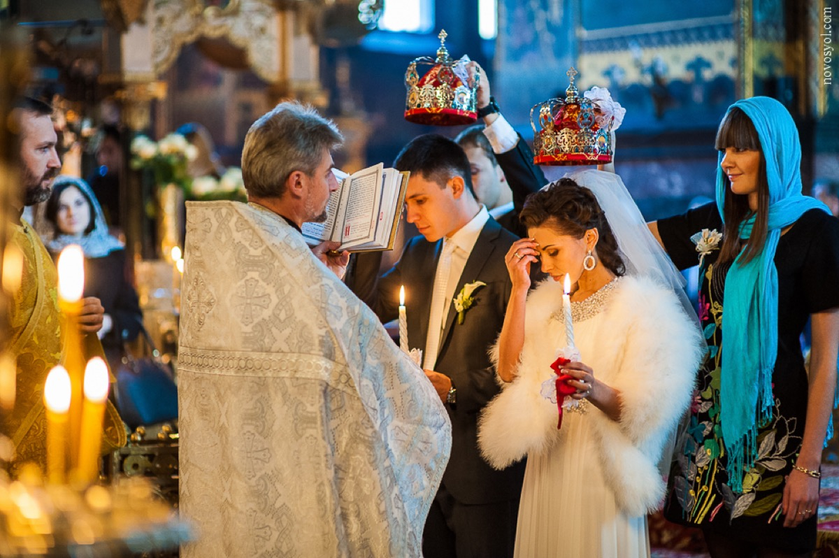 Orthodox wedding crowning in church — bride and groom with candles and crowns